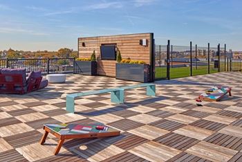 A wooden deck with a table and chairs and a building in the background.